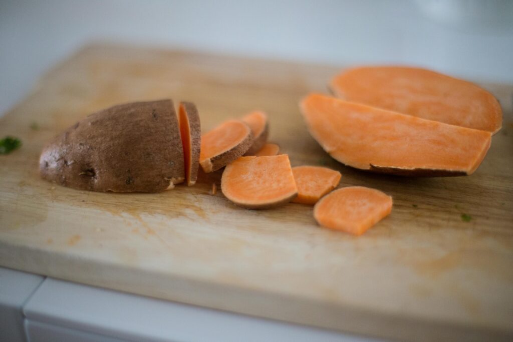 Close-up of sliced sweet potato on a wooden cutting board, perfect for cooking inspiration.